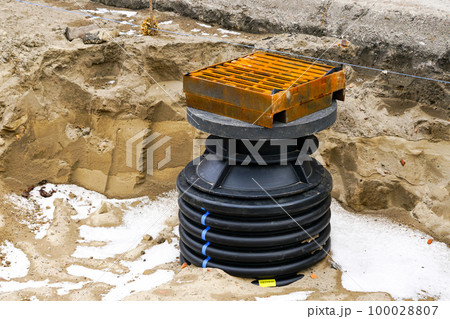 Installation of a new modern plastic rainwater drainage well with cast iron grate in the city street 100028807