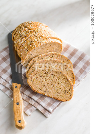 Sliced whole grain bread. Tasty wholegrain pastry with seeds on checkered napkin. 100029677