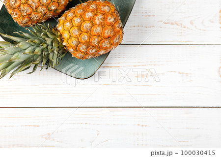 Juicy pineapples in a green plate on a white wooden background. Healthy, detox and dietary nutrition concept. Juicy pineapples in a green plate on a white wooden background. Healthy, detox and dietary nutrition concept. 100030415