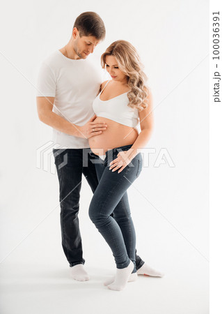 a couple waiting for a child in white T-shirts and jeans on a white background. 100036391