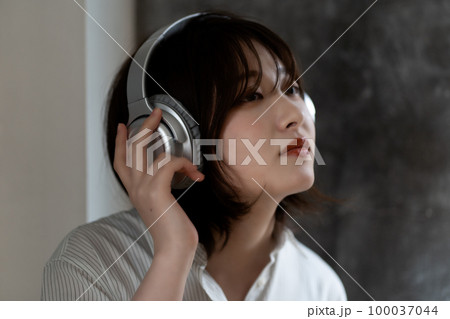 ヘッドフォンで音楽を聴くZ世代の女性 ヘッドフォンで音楽を聴くZ世代の女性 100037044