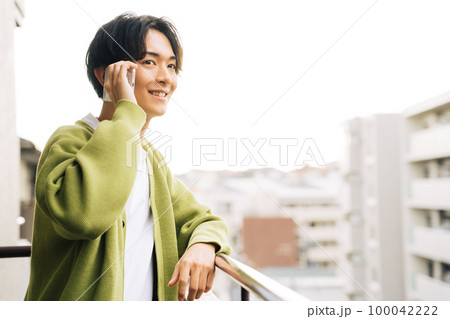 ベランダで電話をする男性 100042222