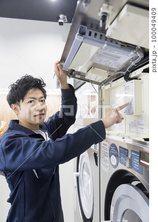コインランドリーのメンテナンスをする作業員男性 100049409