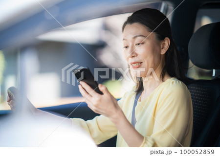 運転しながらスマホを見ているミドル女性 100052859