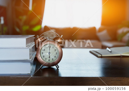 desk clock and books on wooden table. 100059156