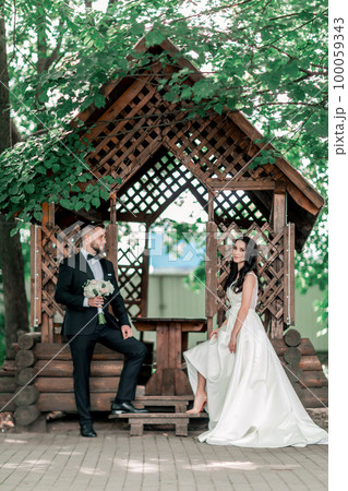 bride and groom standing near the gazebo in the Park 100059343