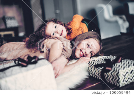 two pretty sisters are having fun in a cozy living room two pretty sisters are having fun in a cozy living room 100059494