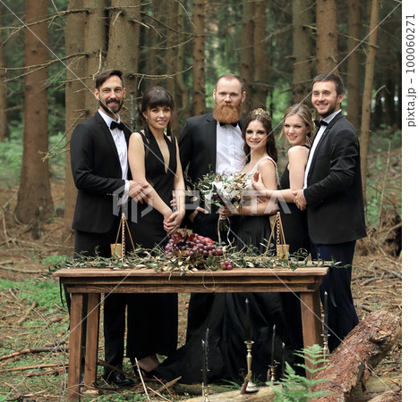 guests and a couple of newlyweds near the picnic table in the woods guests and a couple of newlyweds near the picnic table in the woods 100060271