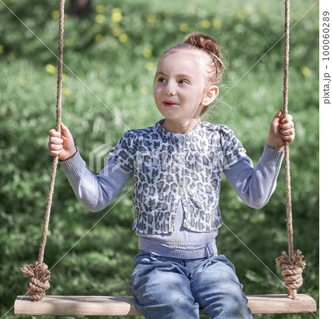 pretty girl sitting on a swing in the garden pretty girl sitting on a swing in the garden 100060289