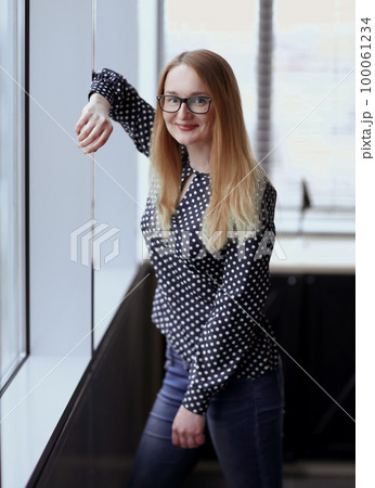 business woman standing near window in office 100061234