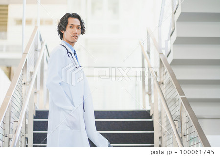 病院の階段を歩く白衣を着た若い男性医師 病院の階段を歩く白衣を着た若い男性医師 100061745