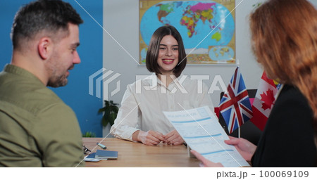 Woman travel agent giving visa application to young woman. Traveler getting ready to travel on vacation. Travelling concept. Woman travel agent giving visa application to young woman. Traveler getting ready to travel on vacation. Travelling concept. 100069109