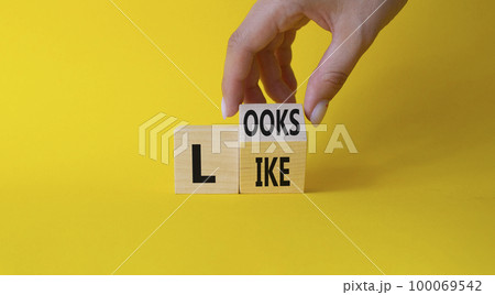 Looks like symbol. Businessman hand Turnes cubes with words Looks like. Beautiful yellow background. Business and Looks like concept. Copy space 100069542