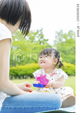 公園でお母さんを見つめ遊ぶ幼い女の子。育児イメージ 100069638