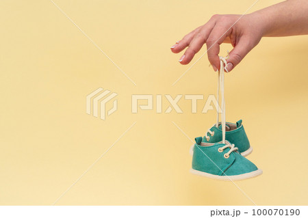 Female hand holding newborn baby shoes with laces 100070190