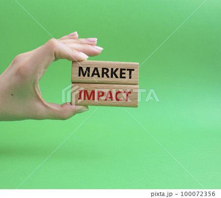 Market impact. Concept word Market impact on wooden cubes. Beautiful green background. Businessman hand. Business and Market impact concept. Copy space. Market impact. Concept word Market impact on wooden cubes. Beautiful green background. Businessman hand. Business and Market impact concept. Copy space. 100072356
