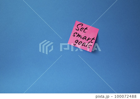 Set smart goals symbol. Concept words Set smart goals on pink steaky note. Beautiful blue background. Business and Set smart goals concept. Copy space. Set smart goals symbol. Concept words Set smart goals on pink steaky note. Beautiful blue background. Business and Set smart goals concept. Copy space. 100072488