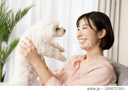 ソファーに座って笑顔で犬を抱く女性 100072561