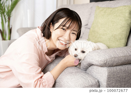 リビングで犬と一緒に微笑む女性 100072677