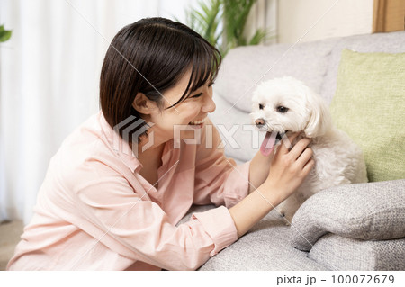 リビングで犬と一緒に微笑む女性 100072679