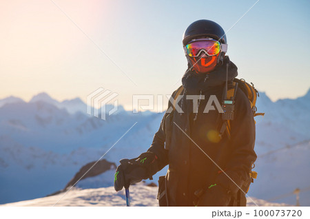Portrait of a skier on the mountain at sunset. Portrait of a woman in a ski resort against the backdrop of mountains and blue sky. Winter sports, security, protection and radio communication Portrait of a skier on the mountain at sunset. Portrait of a woman in a ski resort against the backdrop of mountains and blue sky. Winter sports, security, protection and radio communication 100073720