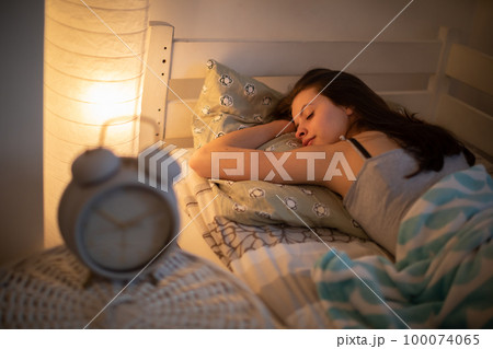 A woman with a slight smile sleeps on her stomach in her bed. A woman with a slight smile sleeps on her stomach in her bed. 100074065