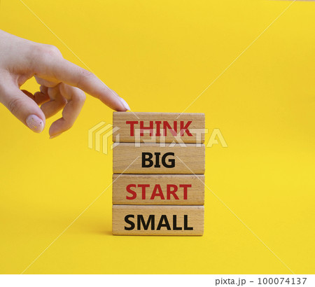 Think big start small symbol. Concept words Think big start small on wooden blocks. Beautiful yellow background. Businessman hand. Business and Think big start small concept. Copy space Think big start small symbol. Concept words Think big start small on wooden blocks. Beautiful yellow background. Businessman hand. Business and Think big start small concept. Copy space 100074137