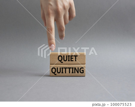 Quiet quitting symbol. Concept word Quiet quitting on wooden blocks. Beautiful grey background. Businessman hand. Business and Quiet quitting concept. Copy space. 100075523