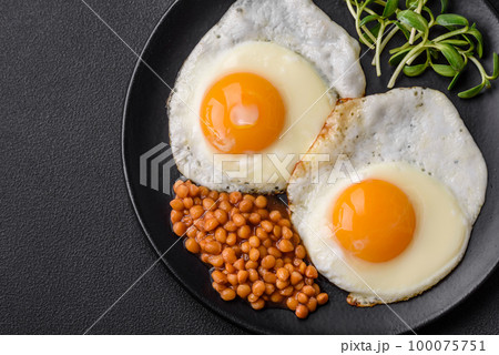 Delicious hearty breakfast consisting of two fried eggs, canned lentils and microgreens 100075751