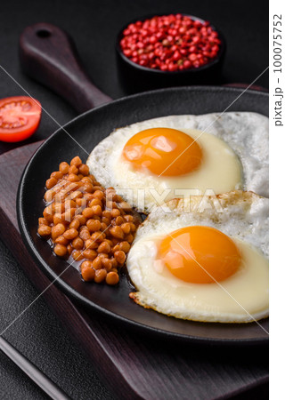 Delicious hearty breakfast consisting of two fried eggs, canned lentils and microgreens 100075752