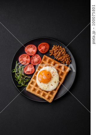 Delicious hearty breakfast consisting of a fried egg, Belgian waffle 100075801