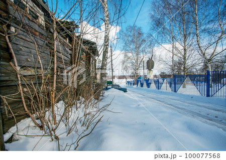 A house with a collapsed roof and walls next to the monument.  about the epic hero Ilya Muromets in Muromek as a symbol of what is happening in Russia 100077568
