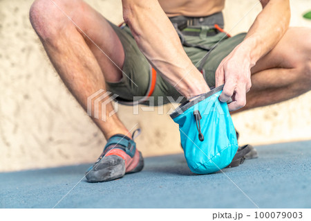applying magnesium to the hands from the bag before climbing the climbing wall 100079003