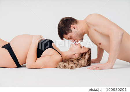 a loving and passionate man and pregnan woman in black underwear on the floor a loving and passionate man and pregnan woman in black underwear on the floor 100080201