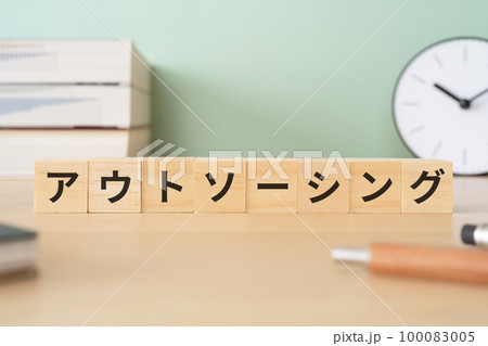 アウトソーシングと書かれたブロックが置かれたデスク 100083005