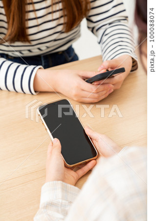 スマホを持つ若い女性の手元 スマホを持つ若い女性の手元 100088074