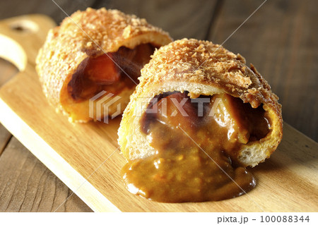 カッティングボードの上の半分にカットされルーが流れ出る熱々カレーパン カッティングボードの上の半分にカットされルーが流れ出る熱々カレーパン 100088344