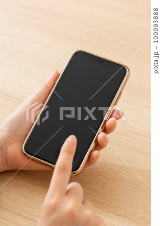 スマホを持つ若い女性の手元 100093888