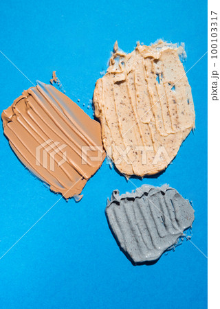 Different swatches of cosmetic products for the face and body on blue background. Texture of skin care cosmetic product. Vertical Different swatches of cosmetic products for the face and body on blue background. Texture of skin care cosmetic product. Vertical 100103317