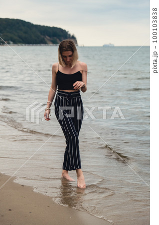 Young woman standing on blurred beachside background. Attractive female enjoying walking the sea shore. travel and active lifestyle concept. Springtime. Relaxation, youth, love, lifestyle solitude Young woman standing on blurred beachside background. Attractive female enjoying walking the sea shore. travel and active lifestyle concept. Springtime. Relaxation, youth, love, lifestyle solitude 100103838