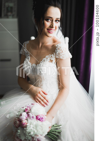 Portrait of stunning bride with long hair posing with great bouquet 100104600