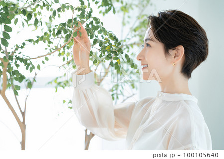 観葉植物を愛でるミドルの女性 観葉植物を愛でるミドルの女性 100105640