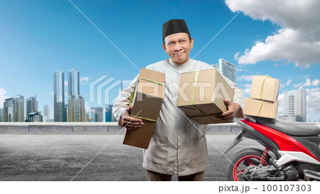 Asian Muslim man carrying a box with a tied box on a motorcycle prepares for mudik Asian Muslim man carrying a box with a tied box on a motorcycle prepares for mudik 100107303