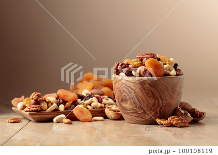 Dried fruits and nuts on a beige ceramic table. 100108119