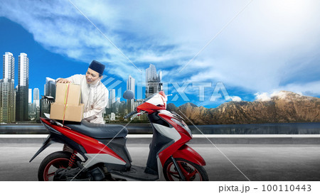 Asian Muslim man tying box on motorcycle prepare for mudik 100110443
