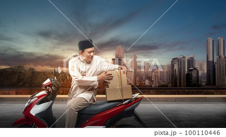 Asian Muslim man tying box on motorcycle prepare for mudik 100110446