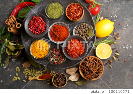 Set of spices and herbs. Indian food. Pepper, salt, paprika, basil, turmeric. On a black wooden board. View from above. Free copy space. 100110571