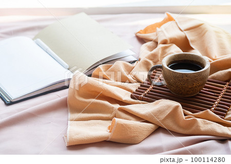 Coffee cup, bamboo tray and open notebook on bed. Good springtime morning. Coffee cup, bamboo tray and open notebook on bed. Good springtime morning. 100114280