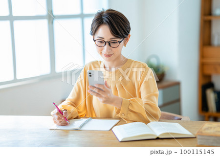 スマホを使って勉強するミドルの女性 100115145