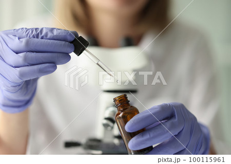 Close-up of scientist taking sample of liquid from bottle with pipette. 100115961